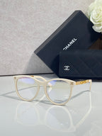 Chanel eyeglasses with cream frames, gold accents, and clear lenses