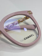 Light pink eyeglasses with engraved Chanel logo on the lens and gold chain detail