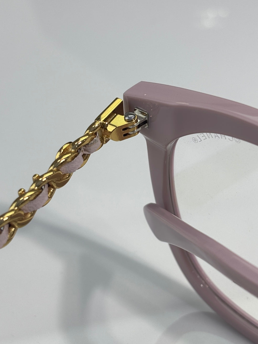 Light pink eyeglass temple with gold chain detail and metal hinge