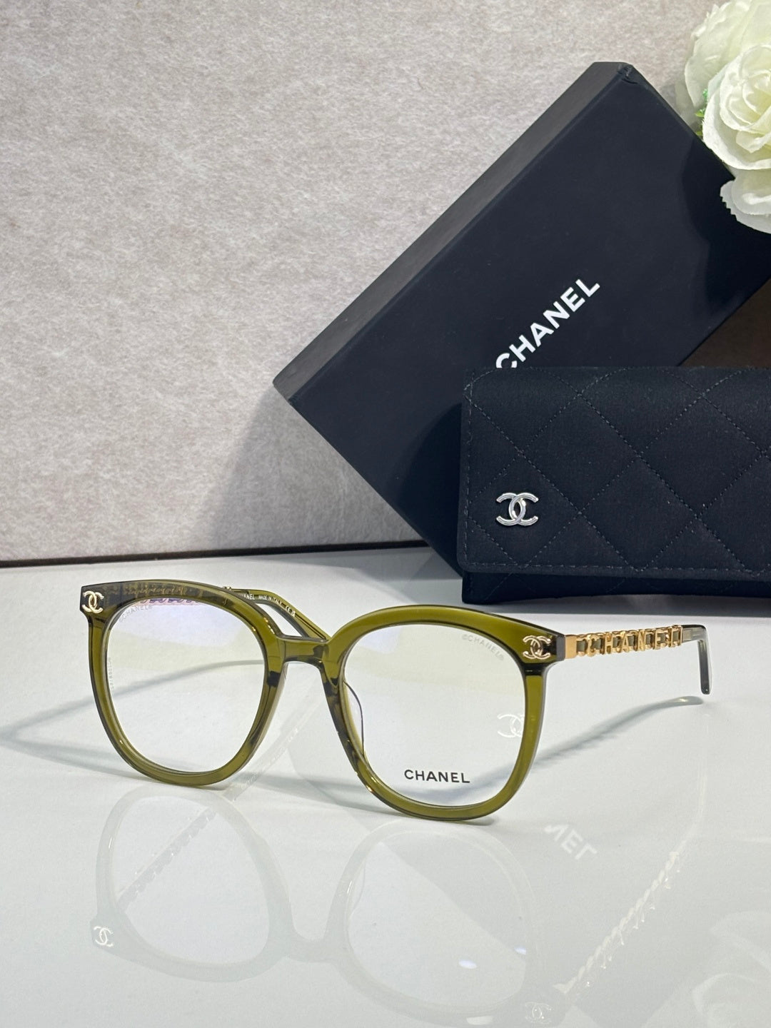 Gold-green rectangular eyeglasses with gold temple chain and Chanel logo detail