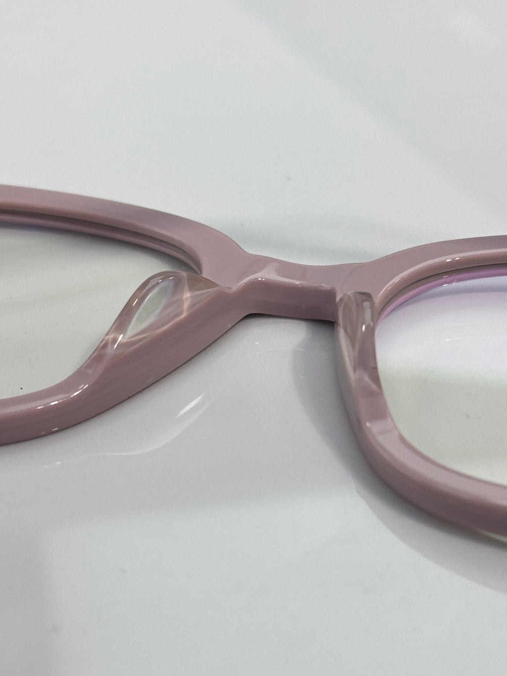 Light pink eyeglasses close-up of the frame bridge and hinge area