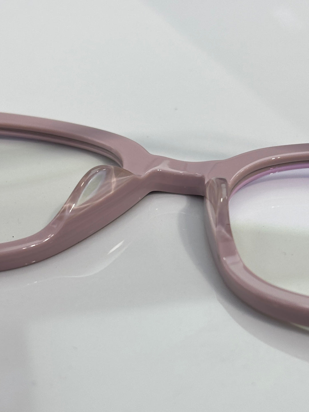Light pink eyeglasses close-up of the frame bridge and hinge area