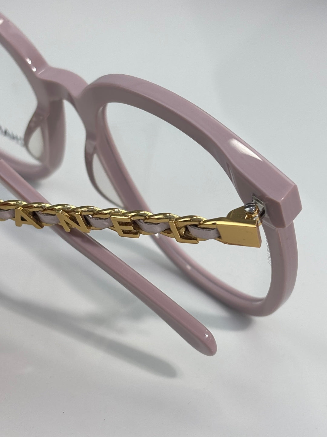 Light pink eyeglasses with gold chain connector on the frame temple