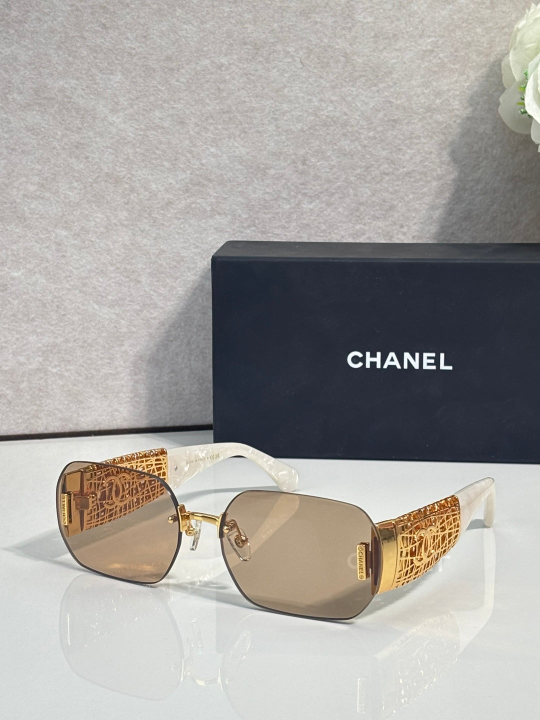 Chanel sunglasses with tan lenses and gold metal frame, textured temple panels
