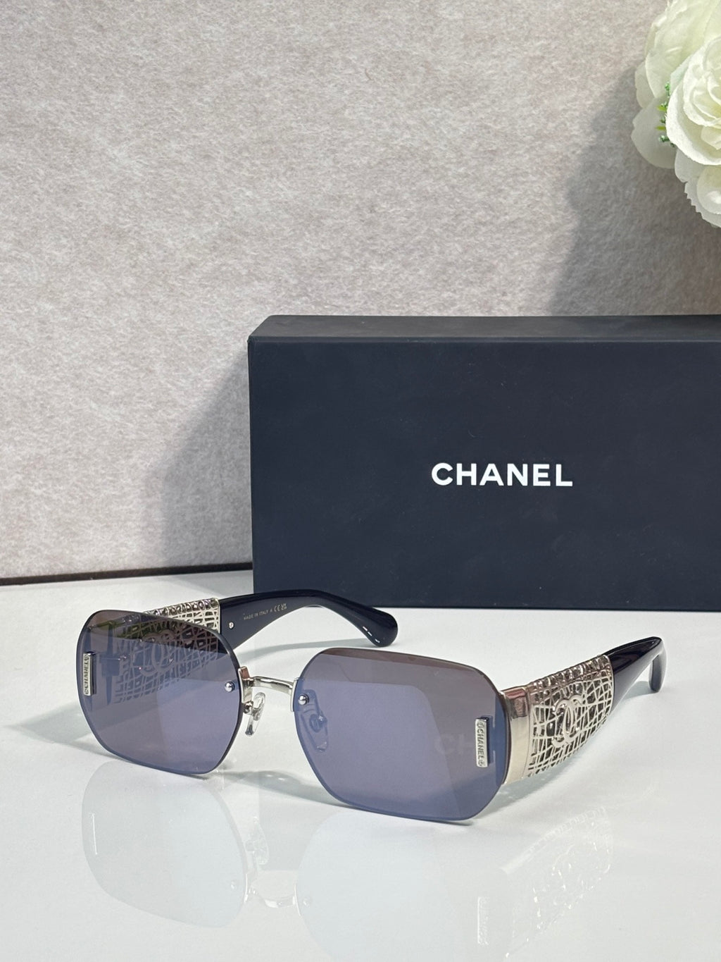 Chanel sunglasses with blue gradient lenses and gold metal frame, textured temple panels