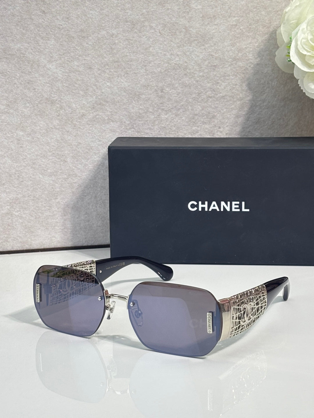 Chanel sunglasses with blue gradient lenses and gold metal frame, textured temple panels