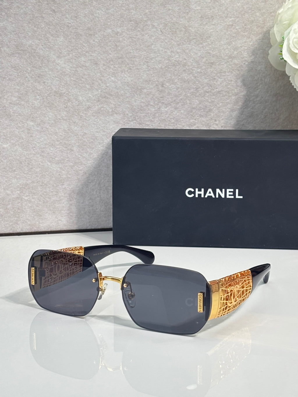 Chanel sunglasses with dark lenses and gold metal frame, textured temple panels