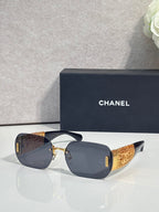 Chanel sunglasses with dark lenses and gold metal frame, textured temple panels
