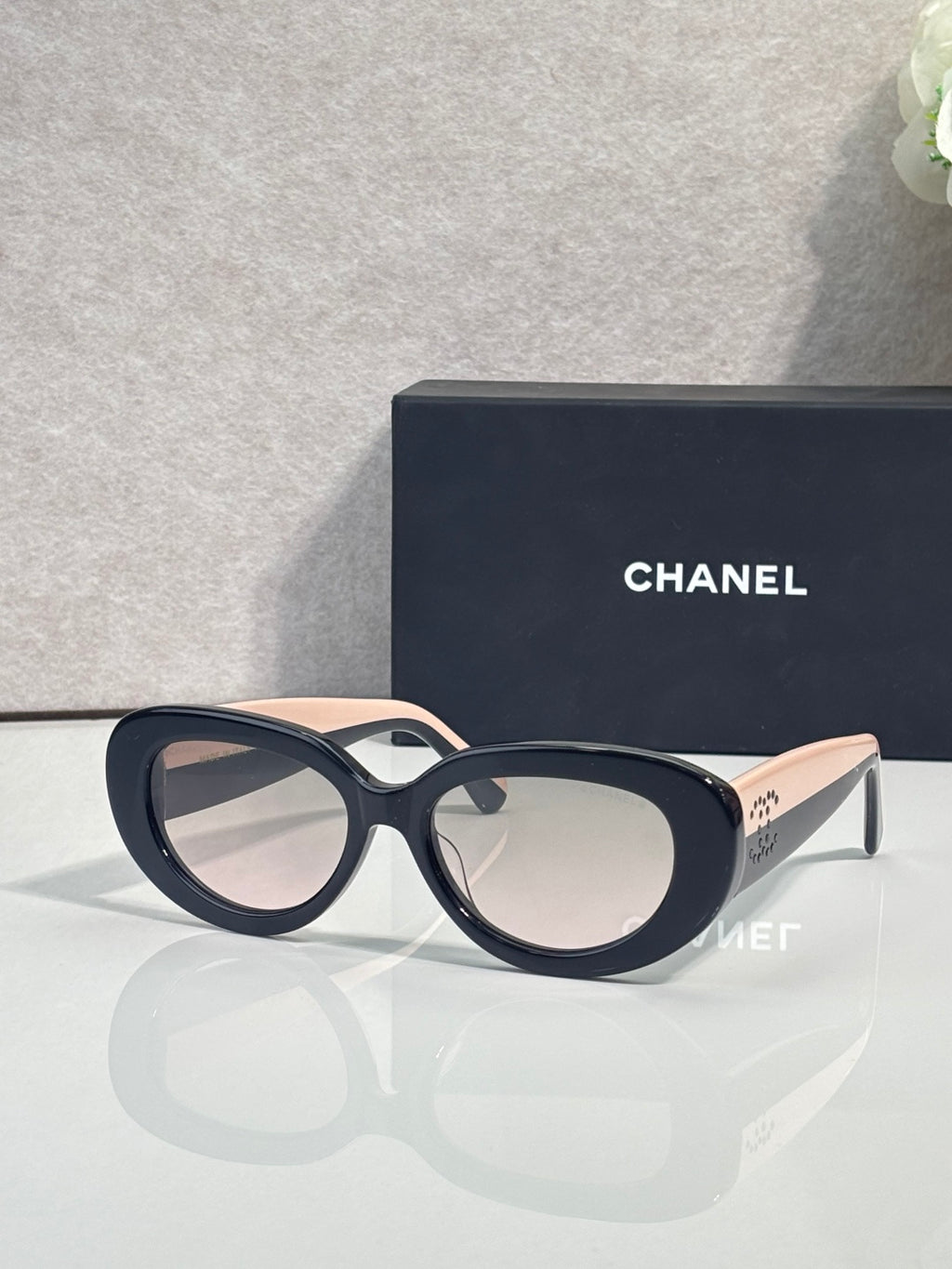 Black round sunglasses with nude-toned side arms and neutral lenses