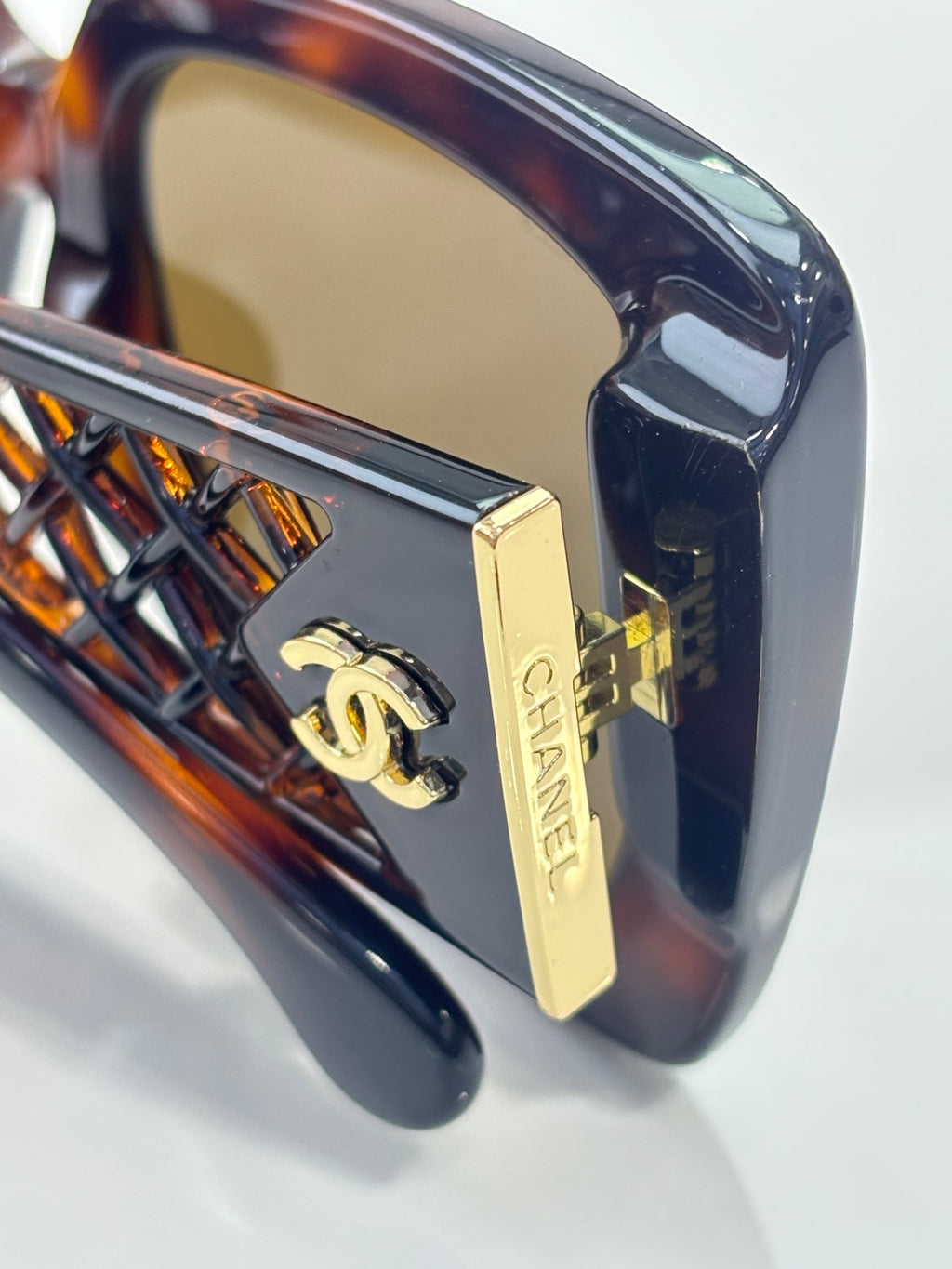 Chanel sunglasses side close-up with gold logo plate on tortoiseshell temple