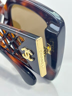 Chanel sunglasses side close-up with gold logo plate on tortoiseshell temple