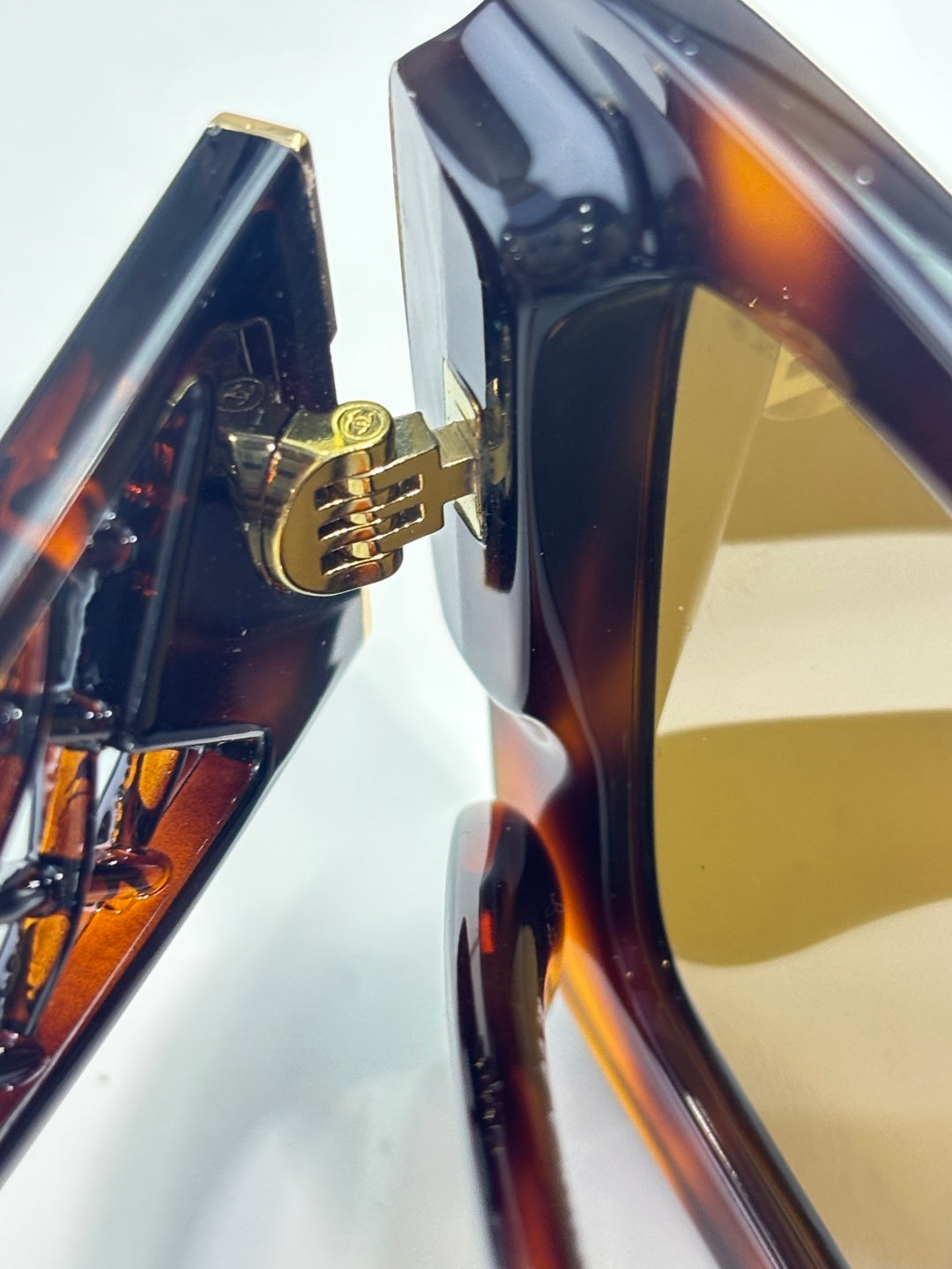 Chanel sunglasses temple close-up with gold logo accent on tortoiseshell frame