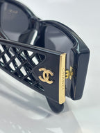 Black sunglasses with gold logo plate and geometric lattice temple frame detail