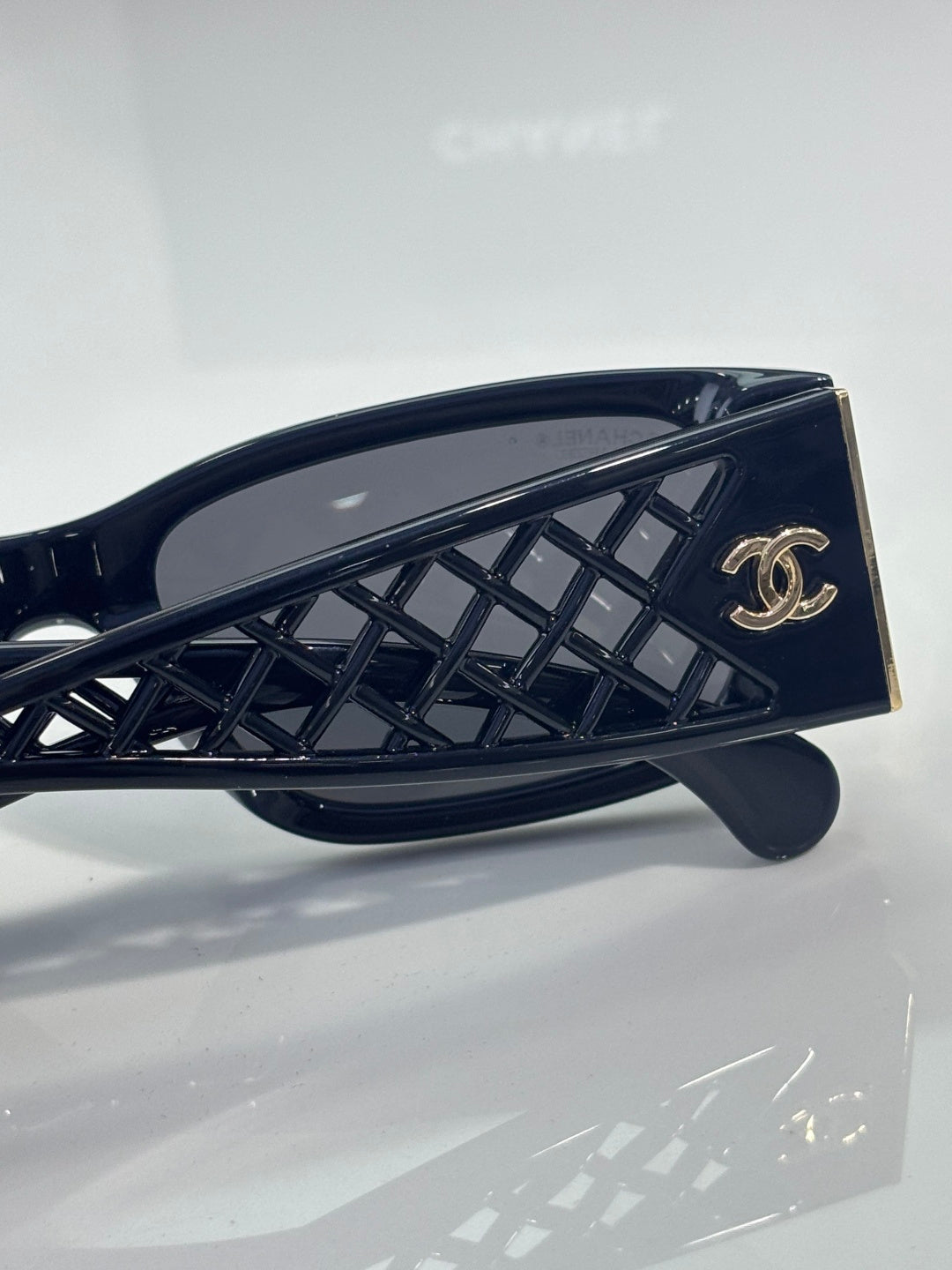 Navy sunglasses temple close-up with gold CC logo on lattice-pattern arm