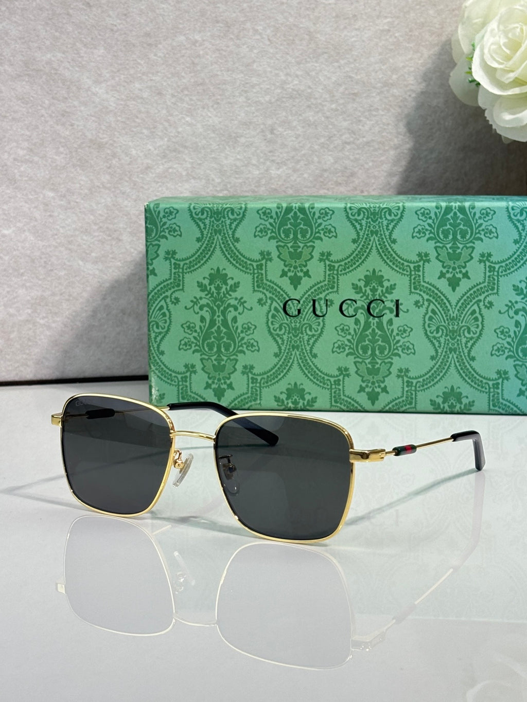 Gucci sunglasses with dark green-tinted lenses and gold-tone frame