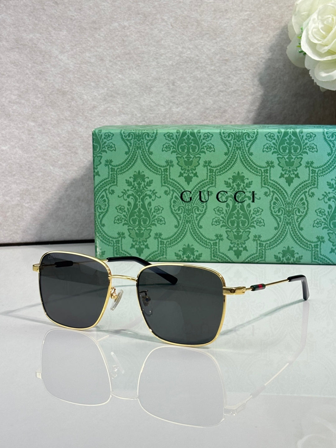 Gucci sunglasses with dark green-tinted lenses and gold-tone frame