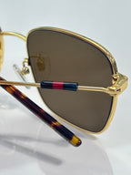 Gucci sunglasses close-up: gold lens rim and striped arms