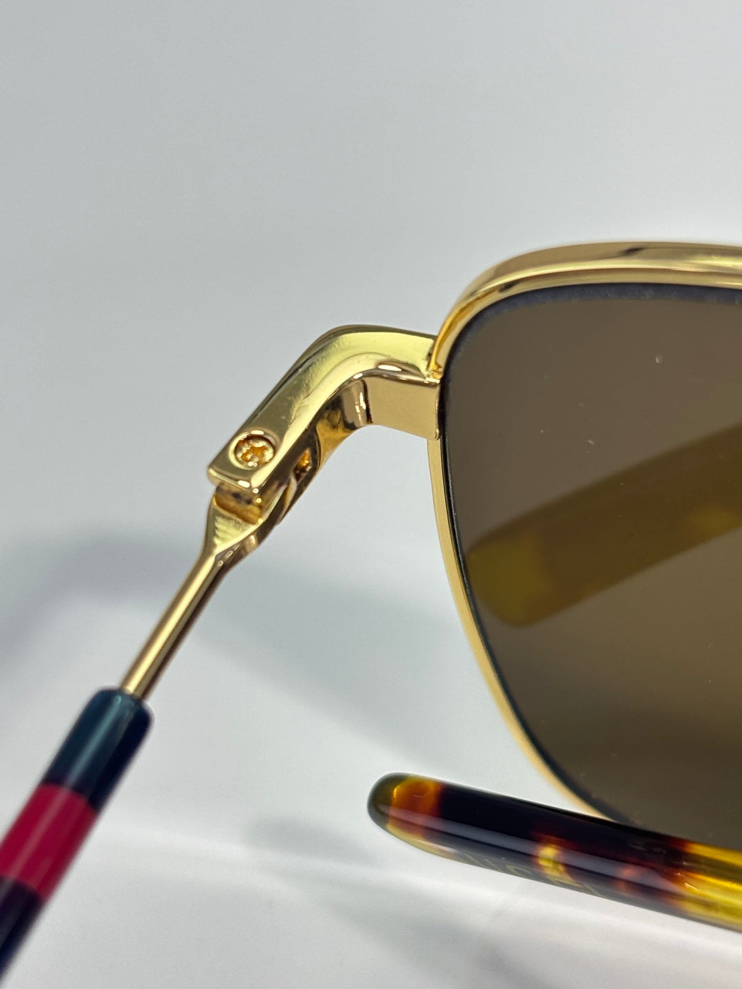 Gucci sunglasses close-up: gold temple with multicolor stripe