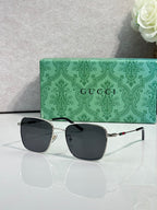 Gucci sunglasses with black lenses, gold-tone frame, and striped temples