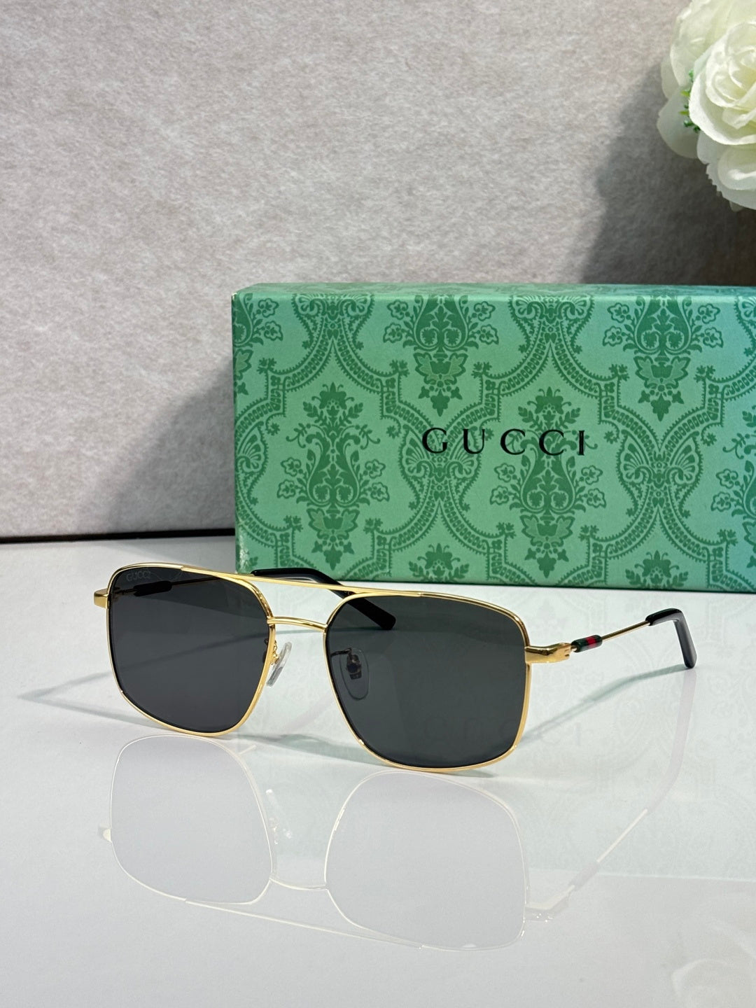Gucci sunglasses with gold-tone frame and dark tinted lenses, wide cat-eye style