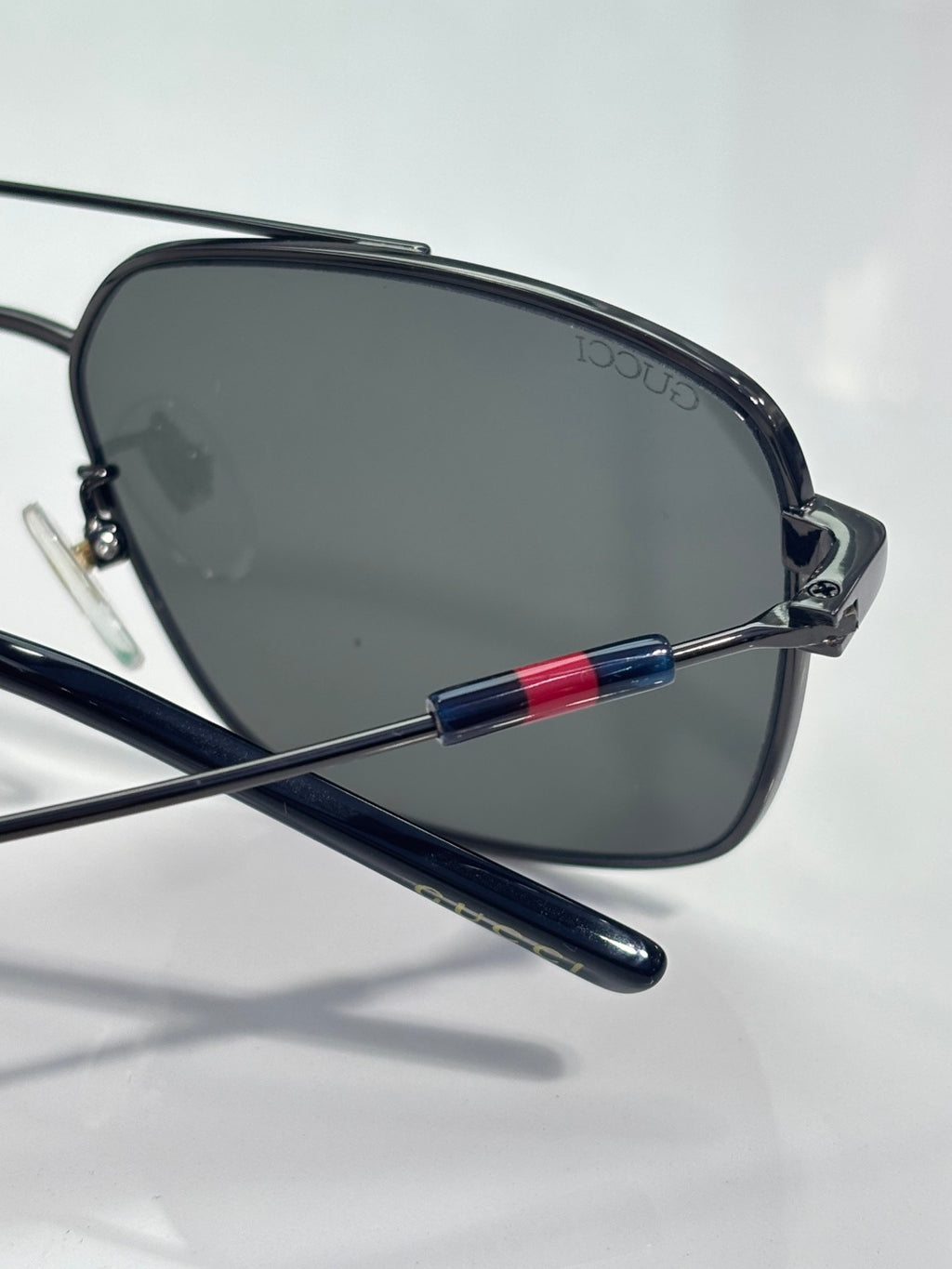 Gucci sunglasses close-up of dark lenses with navy temple and red-blue stripe accents