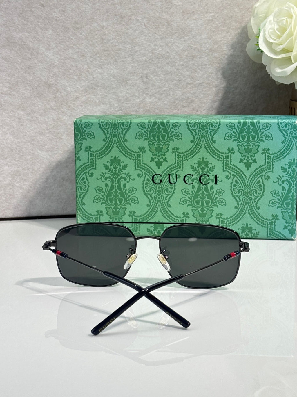 Gucci sunglasses with dark frame and dark tinted lenses, folded cross-view