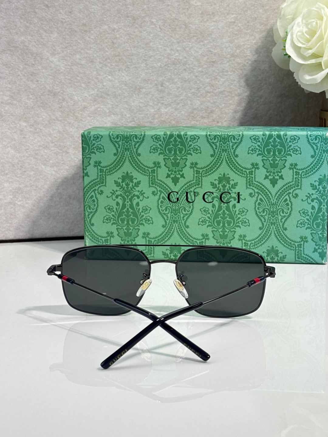 Gucci sunglasses with dark frame and dark tinted lenses, folded cross-view