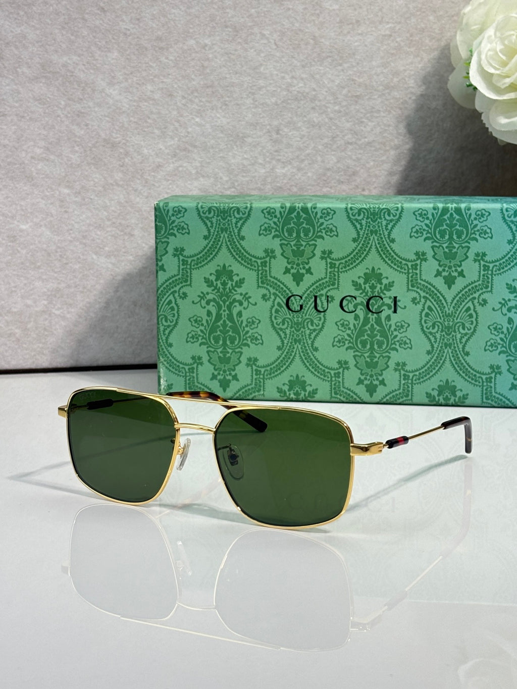 Gucci sunglasses with gold-tone frame and green-tinted dark lenses, cat-eye