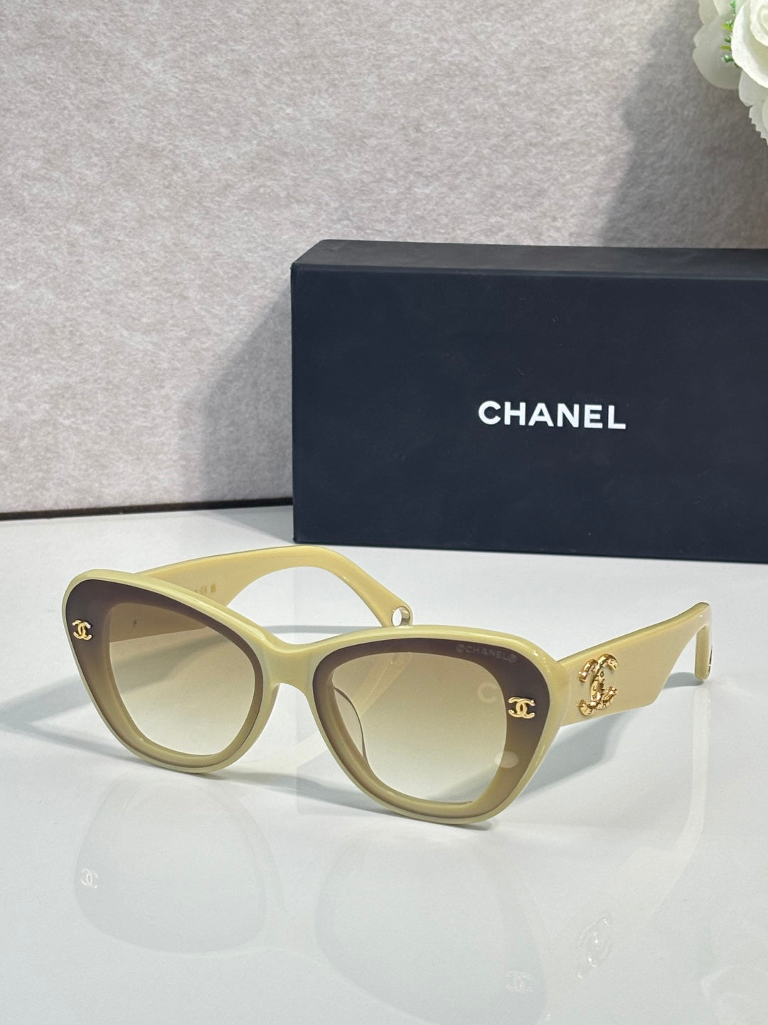 Chanel cat-eye sunglasses with light yellow frames and gold logo details