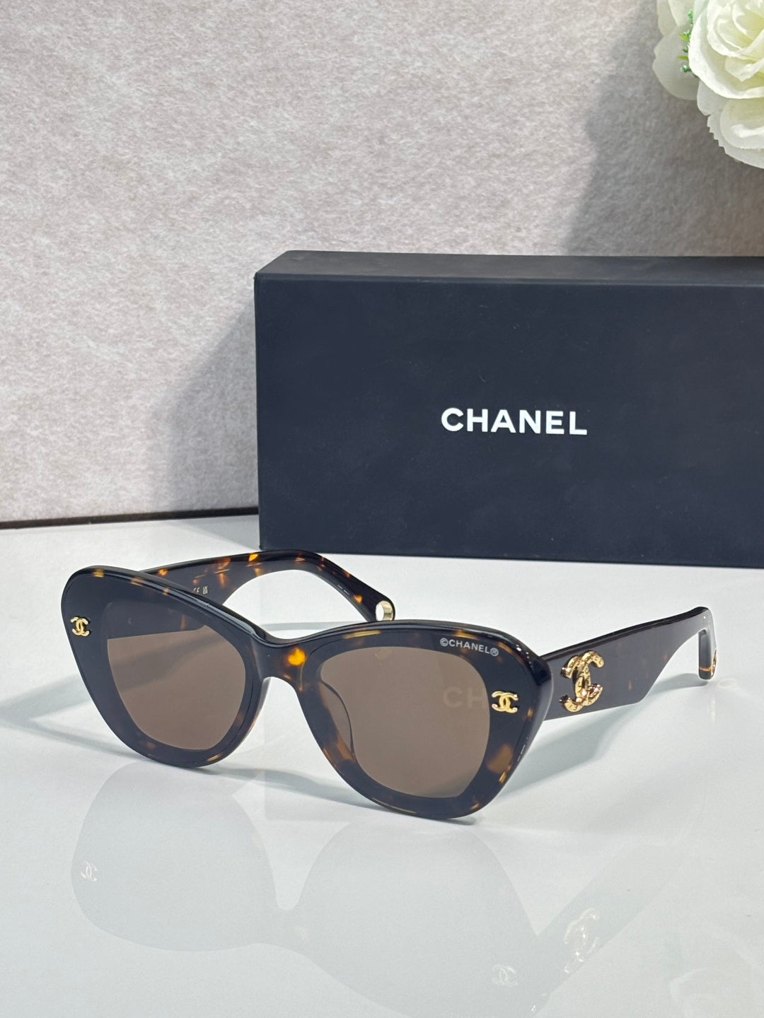 Chanel cat-eye sunglasses with dark frames, gold logo details, tinted lenses