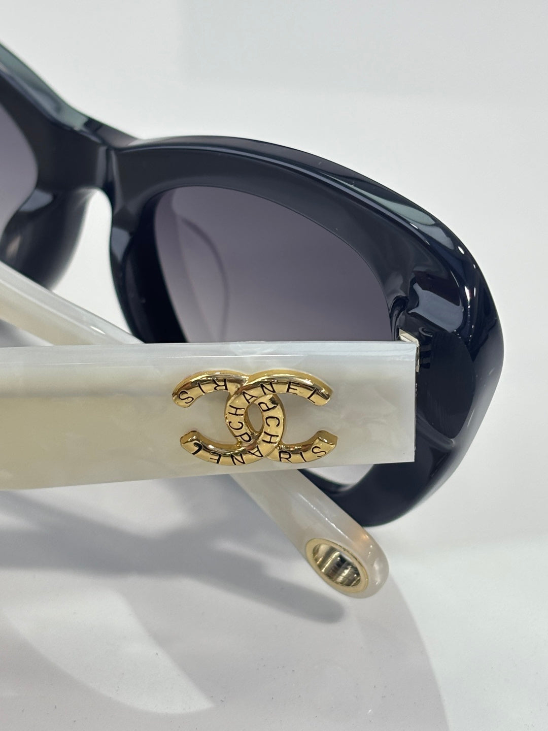 Chanel sunglasses lens and temple close-up with gold logo on cream arm