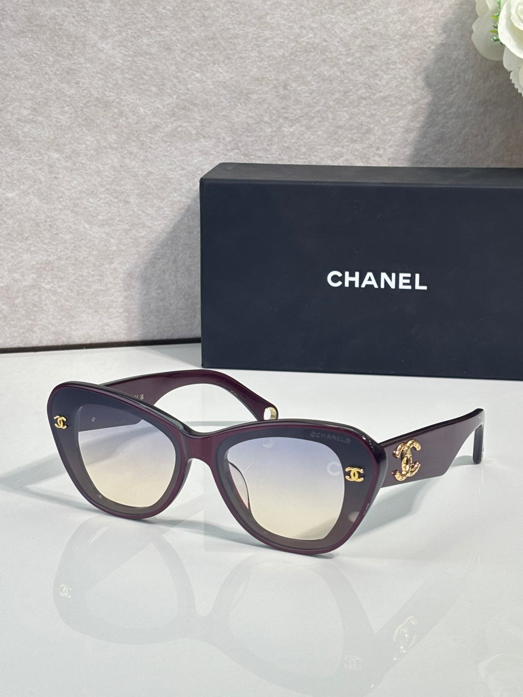 Chanel cat-eye sunglasses with dark purple frames and gold logo hardware