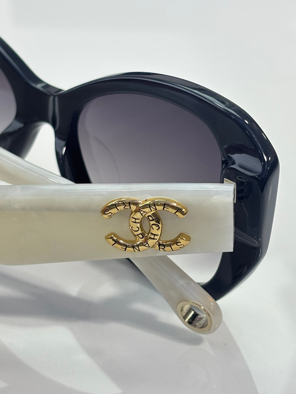 Close-up of dark sunglasses temple with gold logo and earpiece