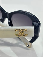 Close-up of dark sunglasses temple with gold logo and earpiece