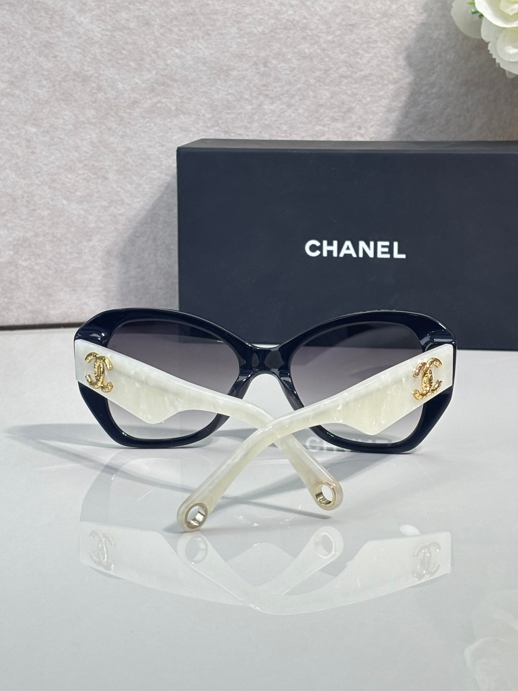 Black Chanel sunglasses with white strap and gold emblem on temples