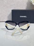 Black Chanel sunglasses with white strap and gold emblem on temples