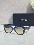 Blue Chanel sunglasses with gold emblem on temples and dark tinted lenses