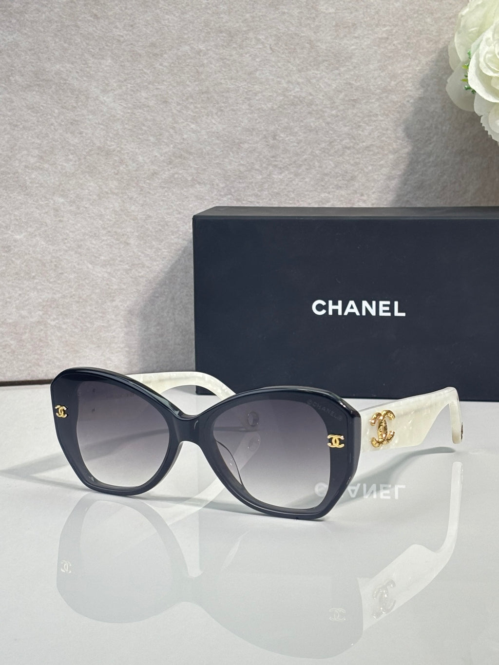 Navy sunglasses with gold emblem on temples, white frame pieces, and tinted lenses