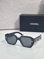 Dark blue square sunglasses with gold logo on temples and tinted lenses