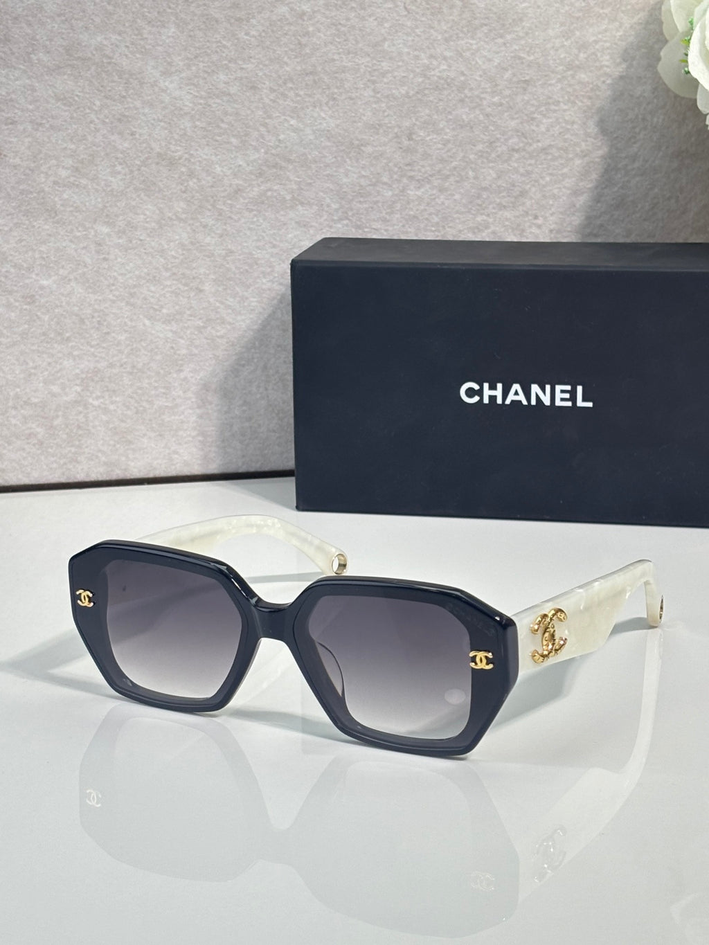 Dark blue square sunglasses with gold logo on temples and tinted lenses