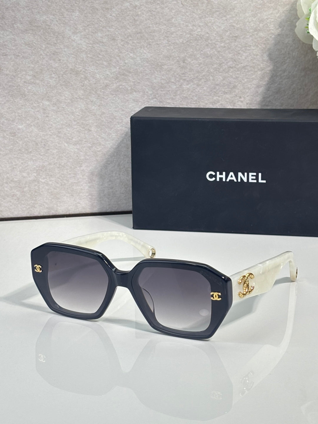 Dark blue square sunglasses with gold logo on temples and tinted lenses