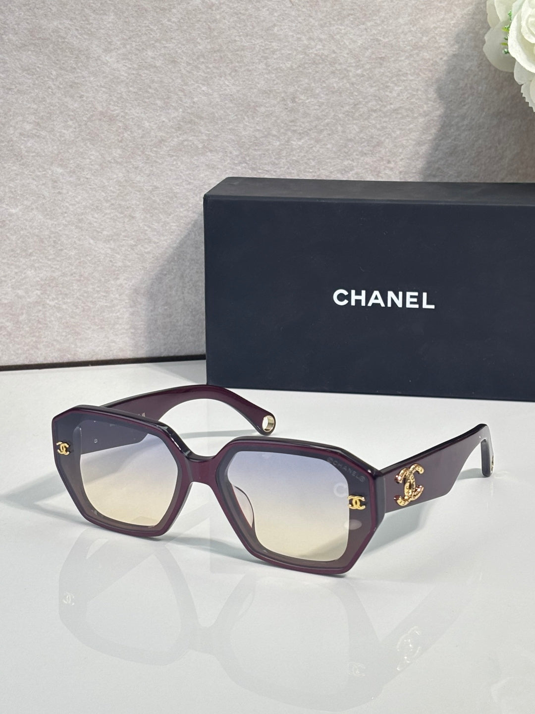 Deep purple square sunglasses with gold logo on temples and tinted lenses