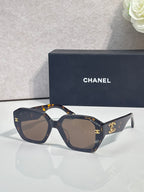 Dark blue square sunglasses with gold logo on temples and tinted lenses