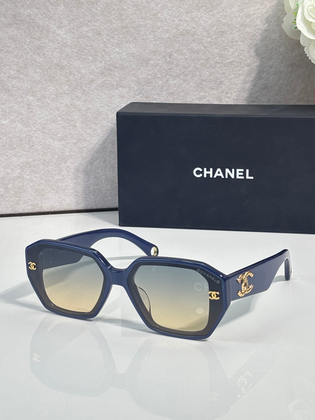 Navy square sunglasses with gold logo on temples and tinted lenses