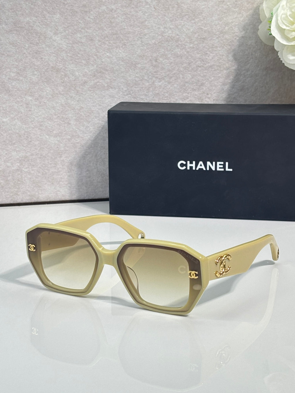 Light gold square sunglasses with gold logo on temples and tinted lenses