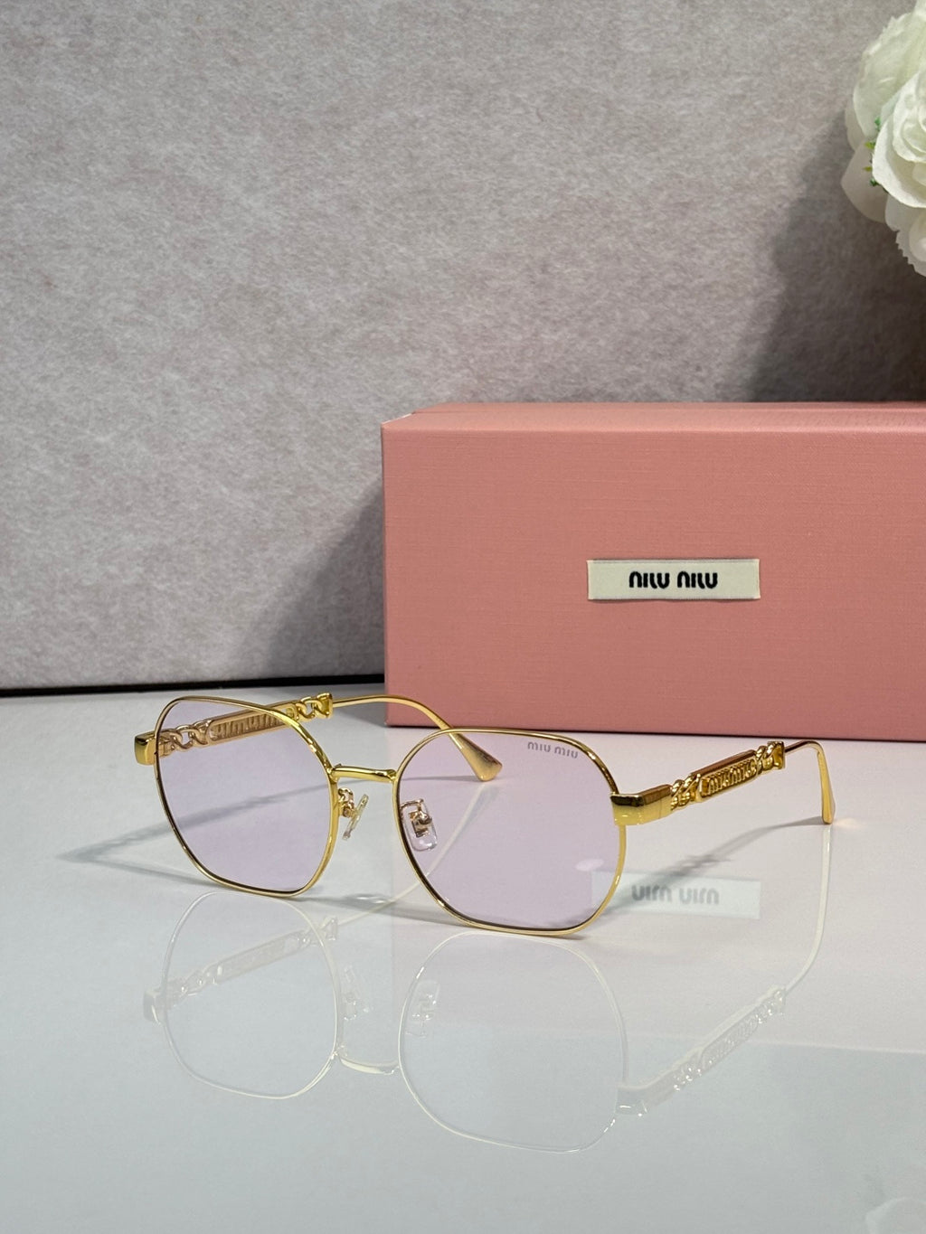 MiuMiu sunglasses with light purple-tinted lenses and gold-tone rounded frames