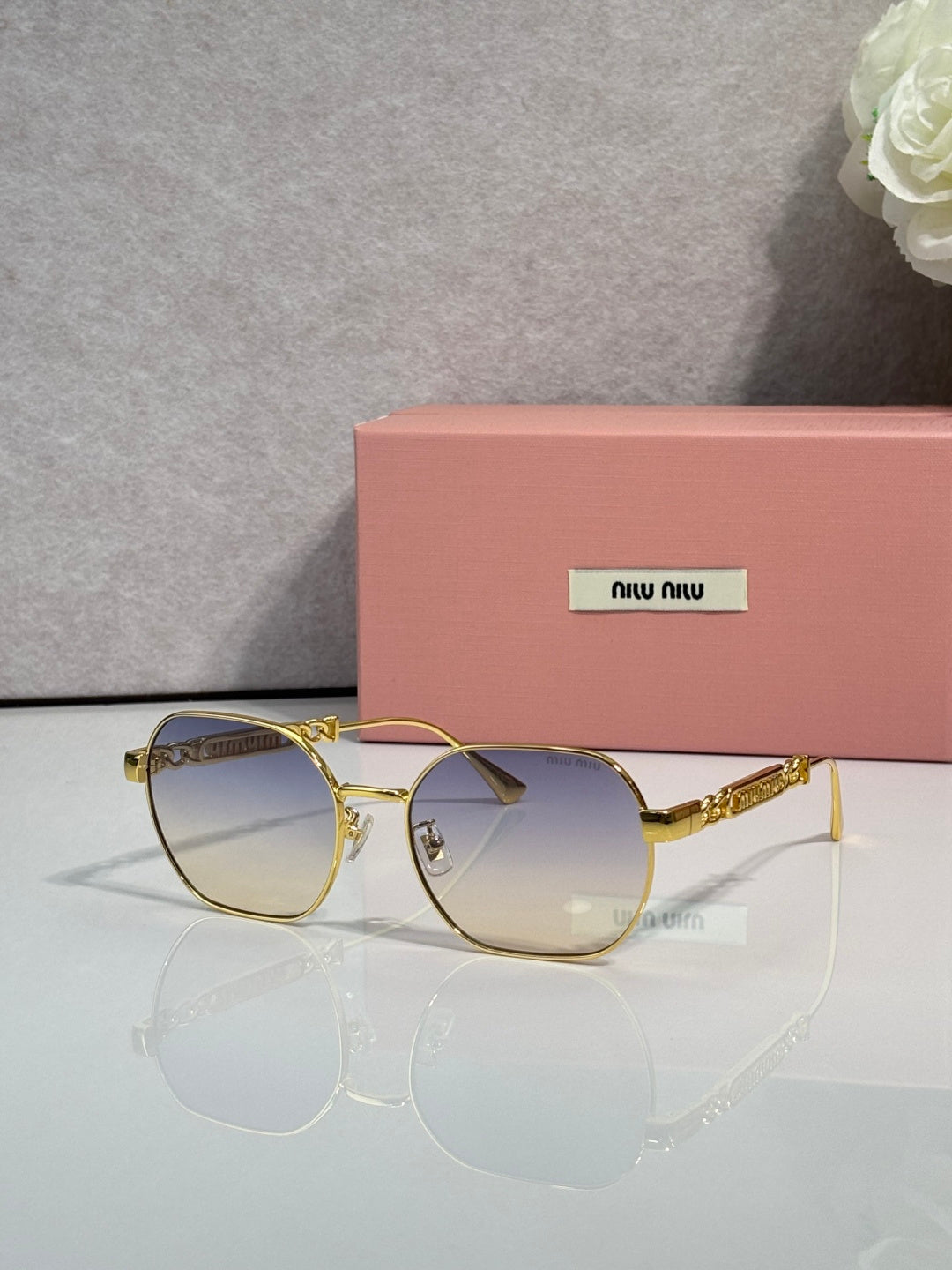 MiuMiu sunglasses with dark blue lenses and gold-tone rounded frames