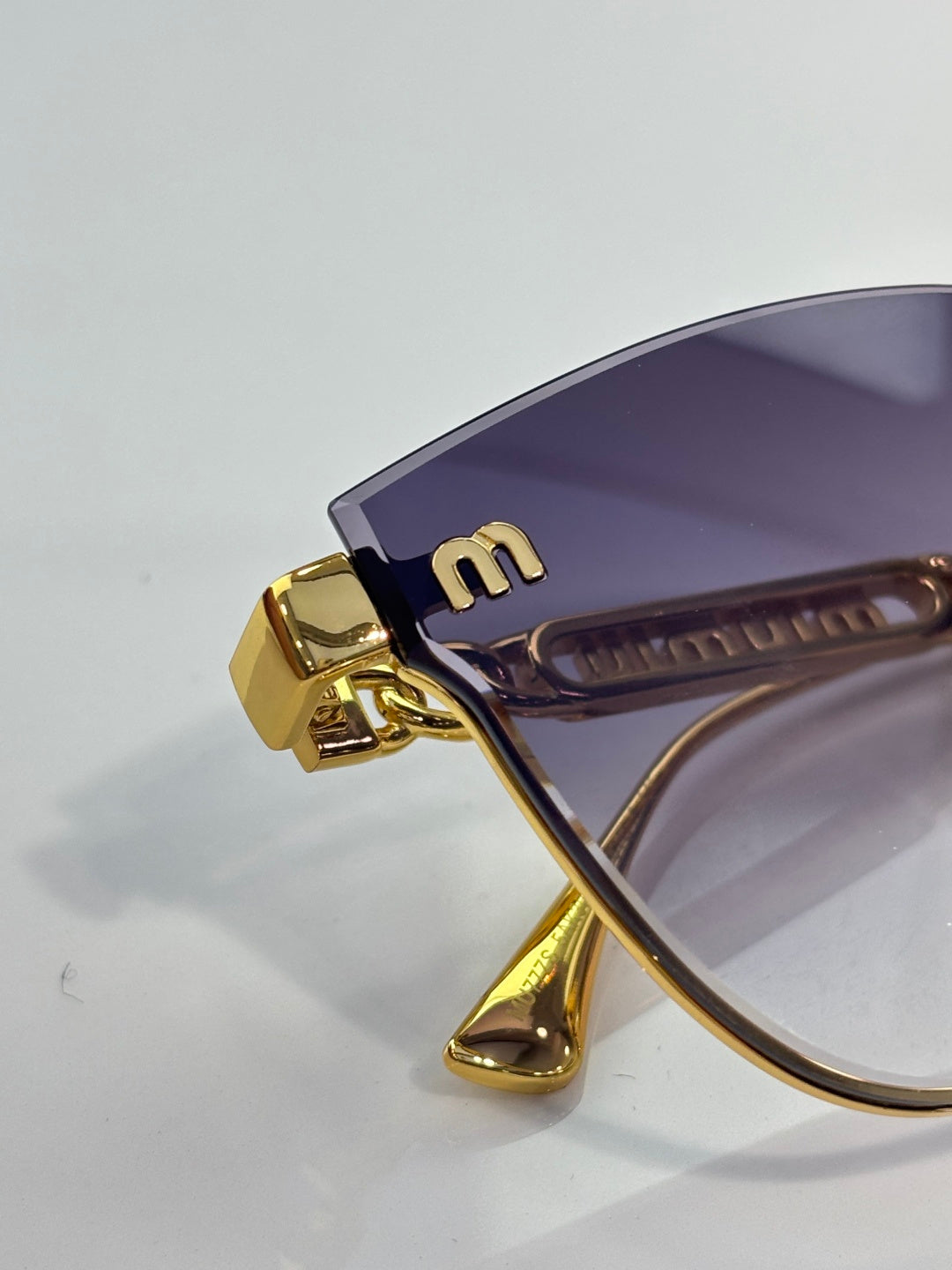 MiuMiu glasses closeup: gold temple hinge with purple inner detail