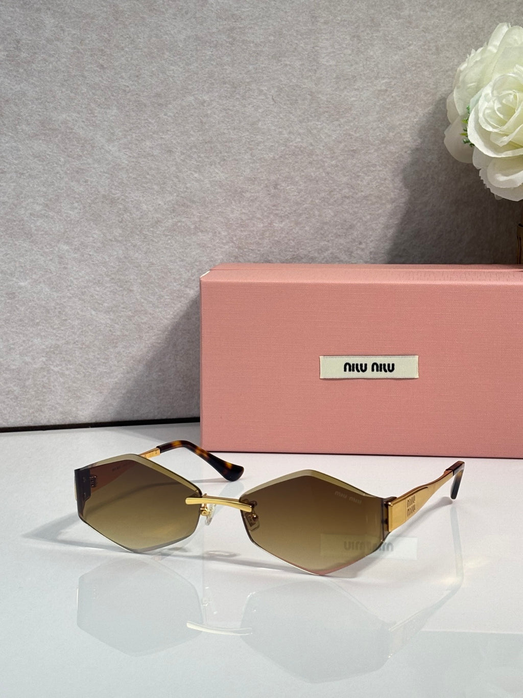 Sunglasses with black frames, gold accents, tan-brown gradient lenses