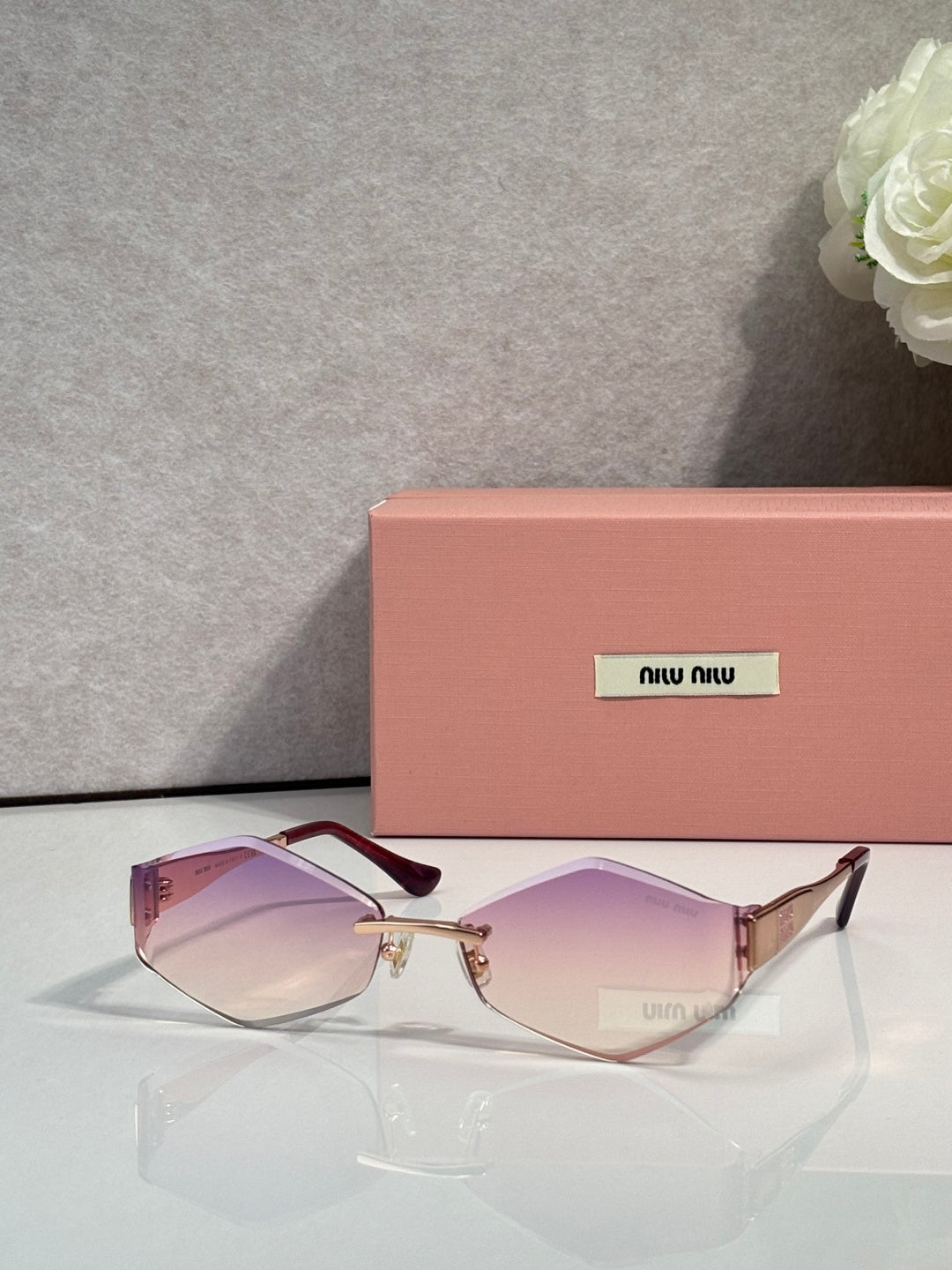 Sunglasses with dark frames, gold accents, light purple gradient lenses